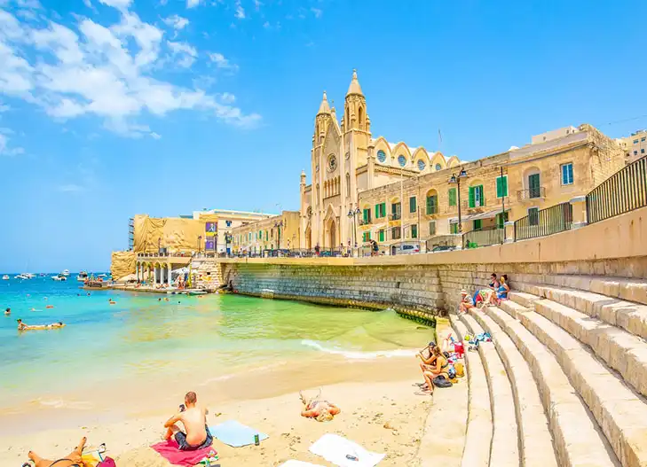 Praia em Malta com prédio histórico ao fundo