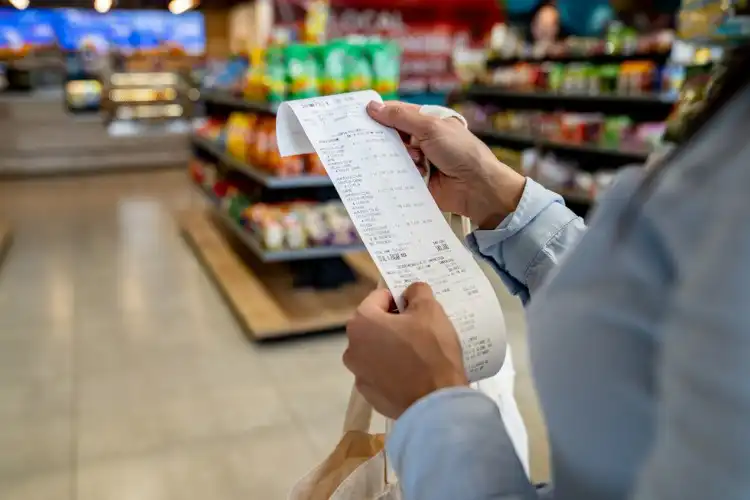 pessoa com fatura do supermercado nas mãos