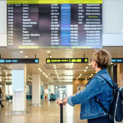 Mulher conferindo quadro de voos em aeroporto