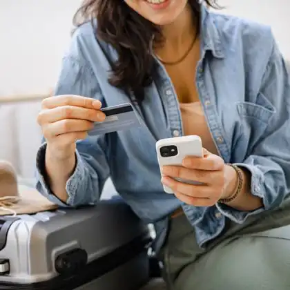 Mulher segurando cartão de débito internacional.