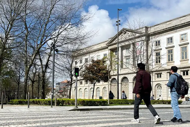 Jovens atravessam a rua em frente à Universidade do Porto, em Portugal