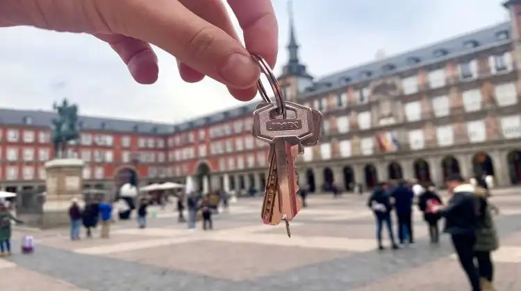 Chaves na mão com a Plaza Mayor em Madrid ao fundo.