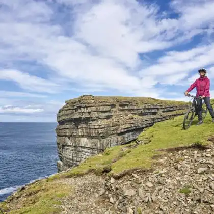 Mulher sênior montando sua mountain bike na Irlanda