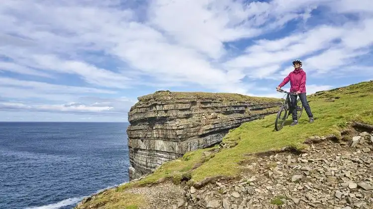 Mulher sênior montando sua mountain bike na Irlanda