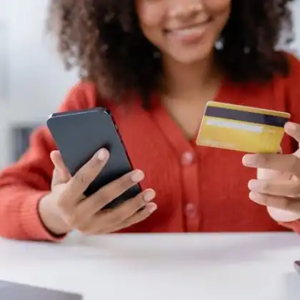 Mulher usando o cartão de crédito e celular para checar o Cashback Wise