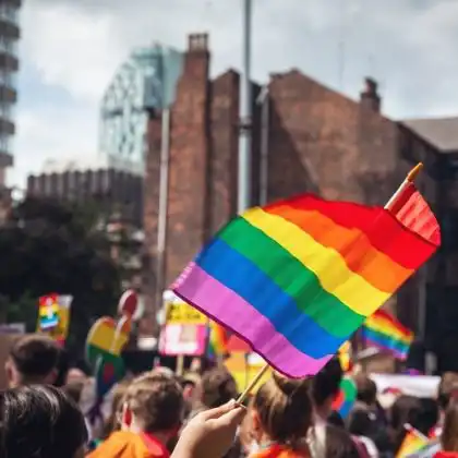 Bandeira LGBTQIA+ erguida em parada na Europa.