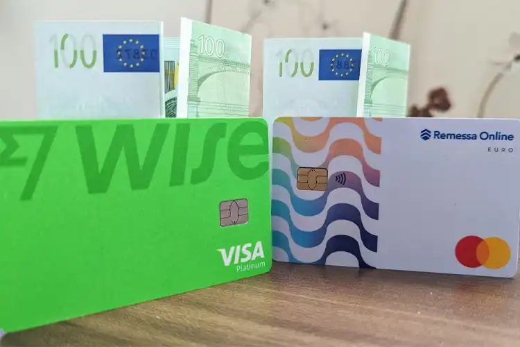 Cartões de contas multimoedas e cédulas de cem euros sobre uma mesa