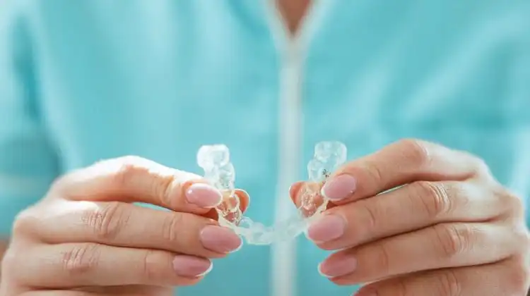 Mulher segurando alinhador de dentes transparente