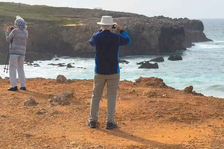 Casal fotografando falésias no litoral de Portugal.