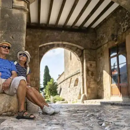 Casal de pessoas na terceira idade sentados em passagem de pedras na Espanha