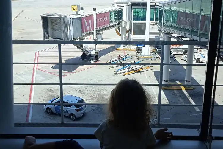 Criança perto do portão de embarque do aeroporto, olhando um avião.