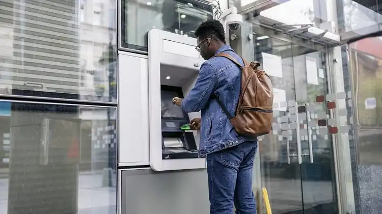 Homem sacando dinheiro em caixa eletrônico.