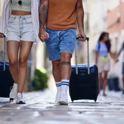 Casal caminha por uma rua a Europa puxando a bagagem