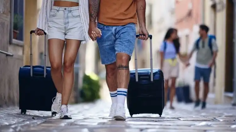 Casal caminha por uma rua a Europa puxando a bagagem
