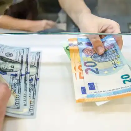 Um homem e uma mulher trocando dólar por euro em uma casa de câmbio