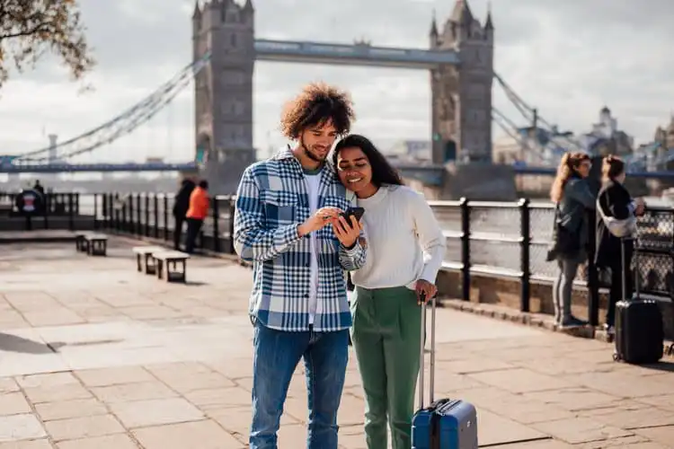 Homem e mulher acionando o seguro viagem Inglaterra pelo celular em Londres. 