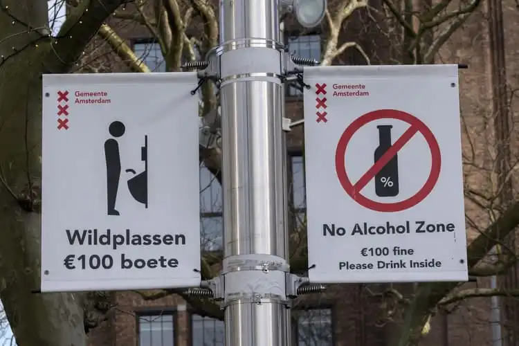 Placas sinalizando que álcool e urina em público são proibidos