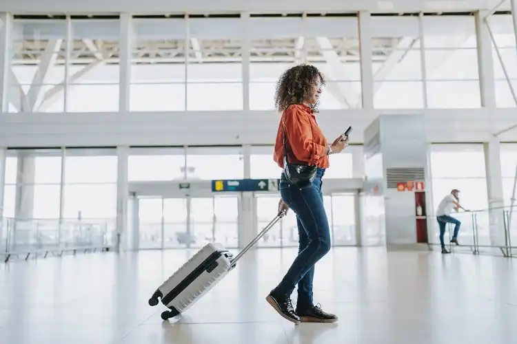 Mulher carregando mala de rodinhas no aeroporto.