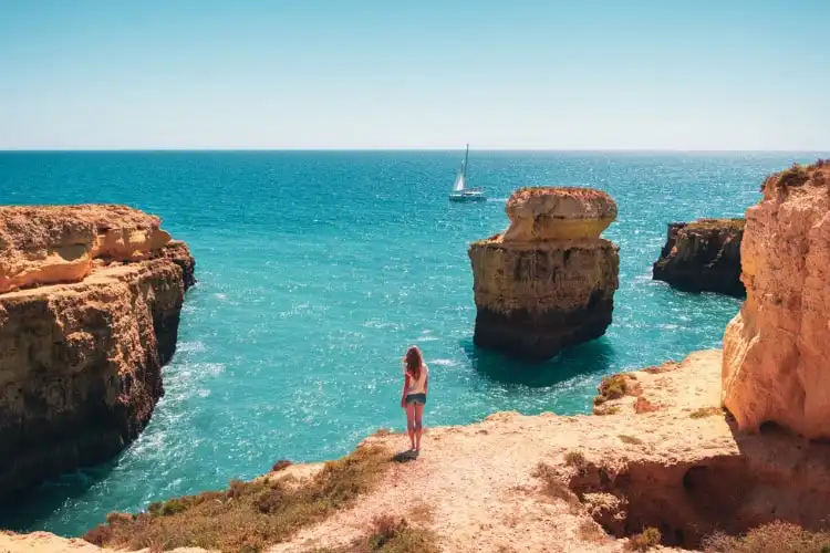 Turista olha para o mar do Algarve, em Portugal