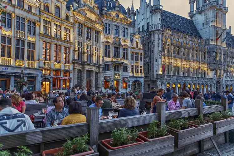 Pessoas sentadas em restaurante na Grand Place, local muito frequentado por quem mora em Bruxelas