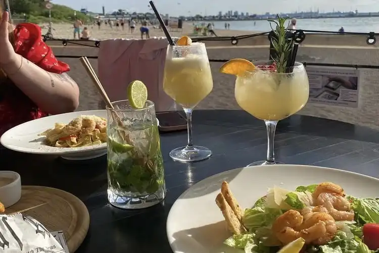 Pratos de comida e bebida em um restaurante à beira da praia em Talín, Estônia