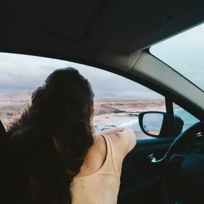 Mulher admirando paisagem de dentro do carro.