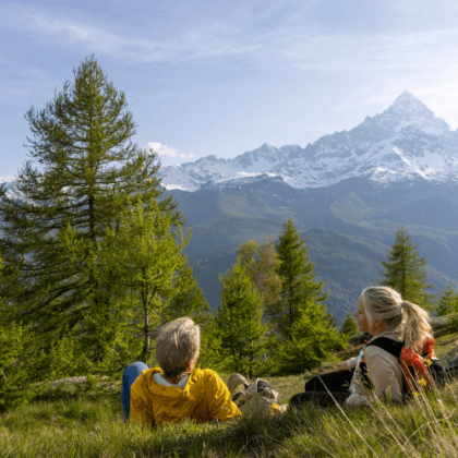 Um casal de terceira idade observando a paisagem com montanhas ao fundo