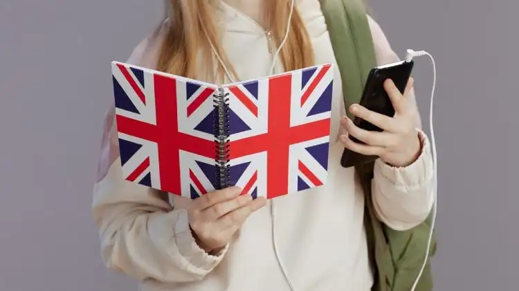 Menina com mochila segurando um celular e um caderno com a capa do Reino Unido.