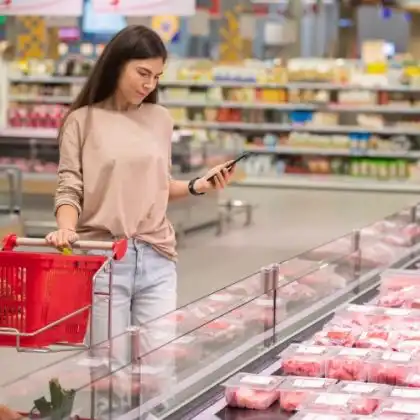 Mulher comprando carne em Portugal no supermercado.