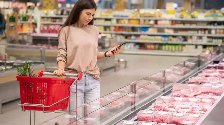 Mulher comprando carne em Portugal no supermercado.