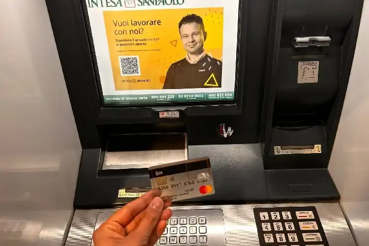 Mãos segurando cartão de débito em banco na Itália