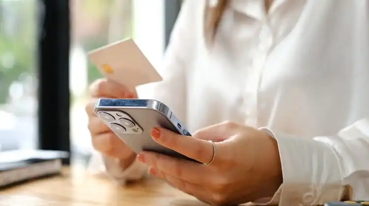 Mulher pagando contas pelo cartão de débito internacional online.