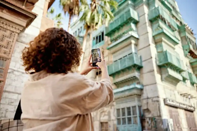Mulher usa celular para fotografar arquitetura.