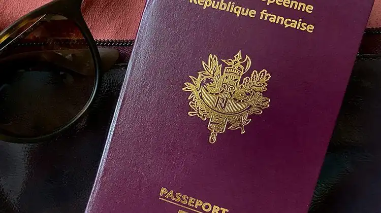 o passaporte francês ao lado de óculos escuros