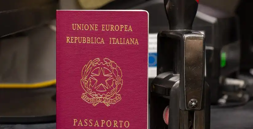 Passaporte italiano ao lado de carimbo
