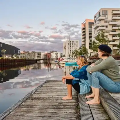 Duas mulheres à beira de um rio numa das cidades mais felizes da Europa.