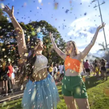 Duas mulheres jogando confete em festa de carnaval.