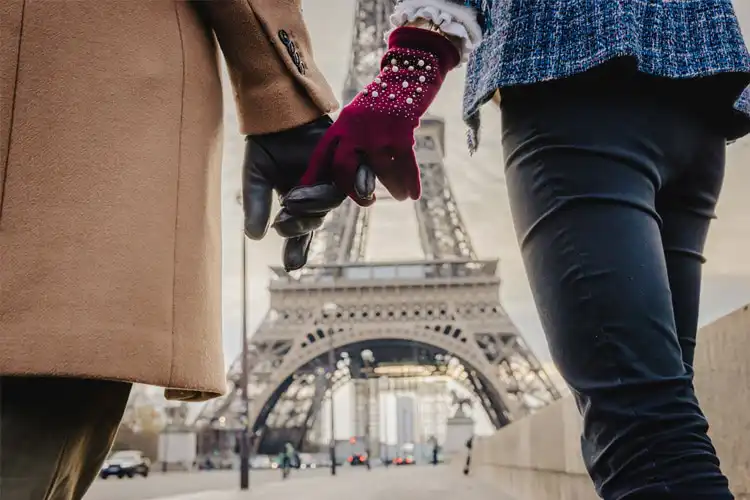 Casal de mãos dadas em frente à Torre Eiffel