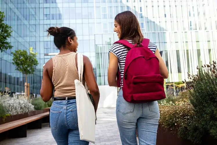 Duas mulheres caminham em direção a uma universidade