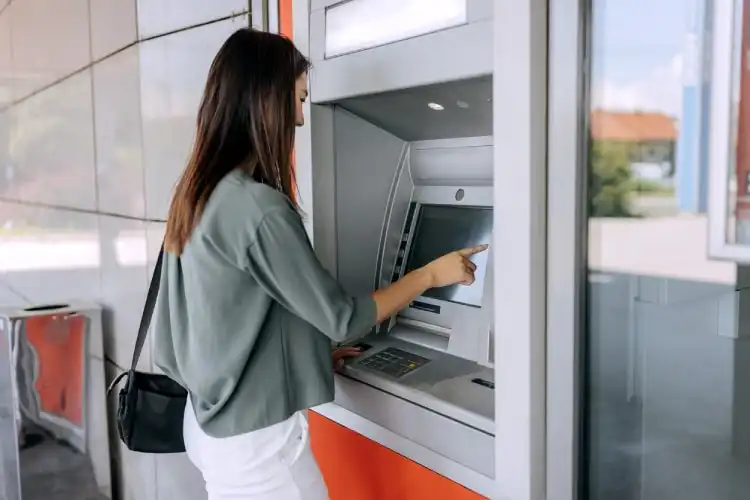 Mulher sacando dinheiro em caixa automático