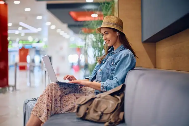 Mulher sentada com notebook procurando seguro viagem