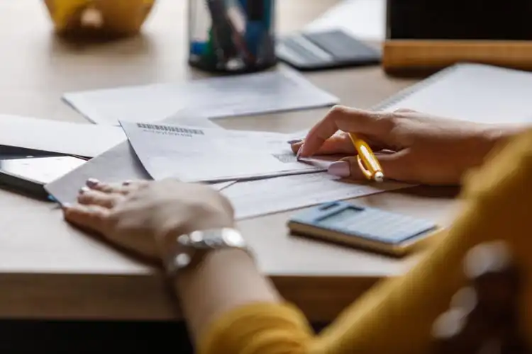 Pessoa com documentos e calculadora sobre a mesa