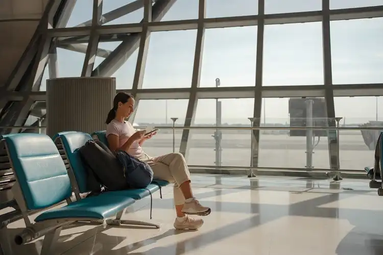 Mulher em aeroporto antes de viajar, olhando para documentos.