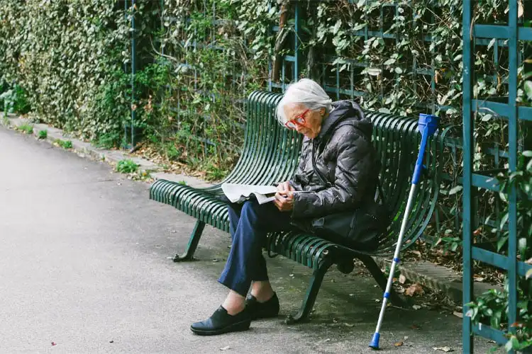 Senhora idosa lendo um livro em um banco de Paris