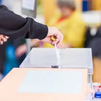 Pessoa inserindo envelope com voto durante as eleições na Espanha