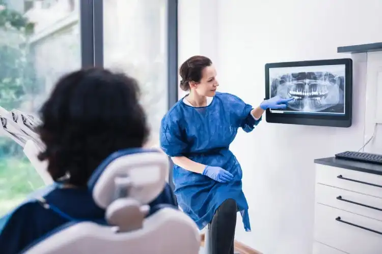 Dentista explicando exame de raio-X para paciente. 