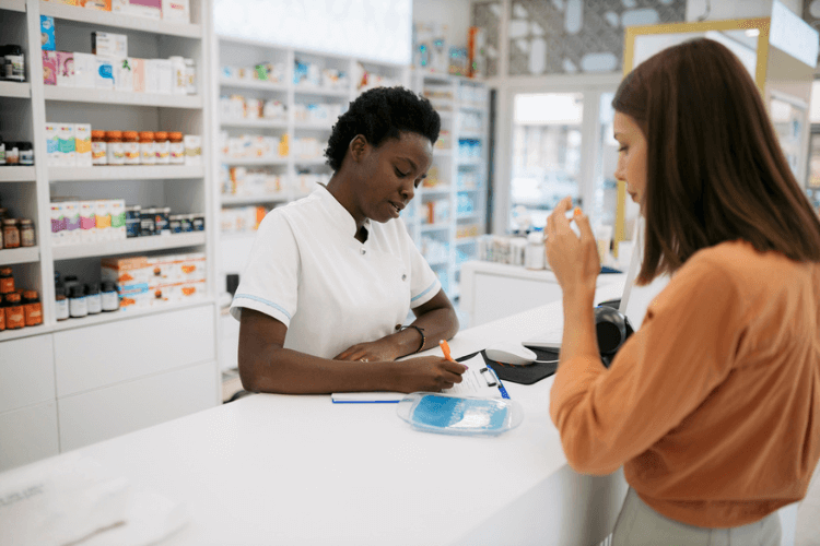 Mulher pegando medicamentos com ticket sanitário na farmácia.