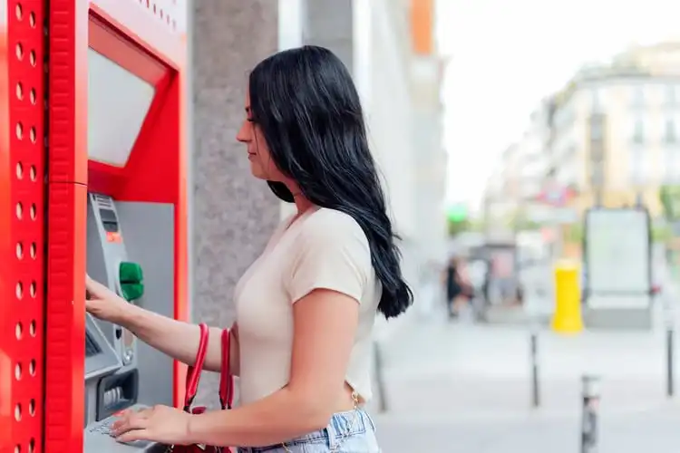 Mulher sacando seus pagamentos internacionais em um caixa eletrônico no exterior. 