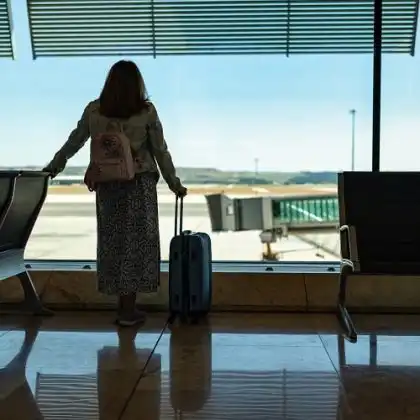 Mulher em aeroporto, após sofrer atraso de voo e perda de conexão.