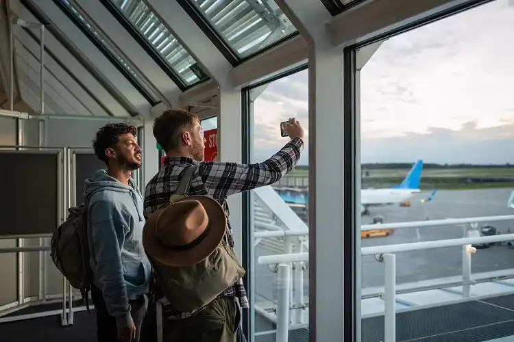 Casal de homens fotografando um aeroporto.